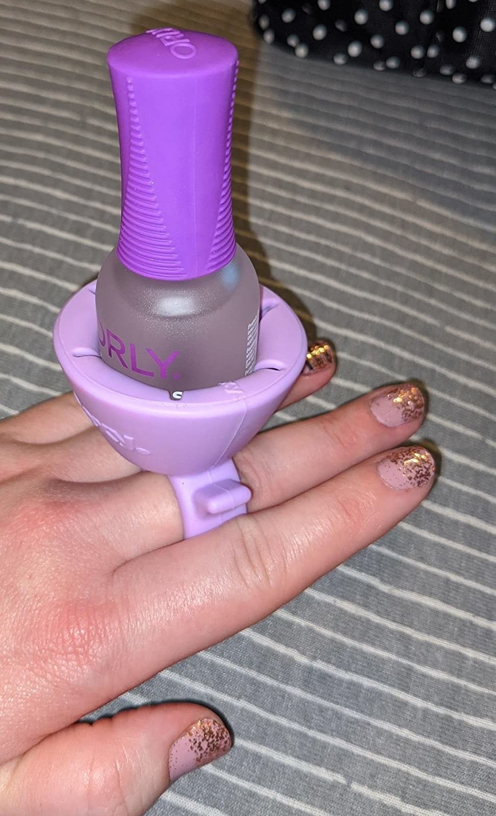 A reviewer showing their painted nails with the polish holder securely on their fingers 