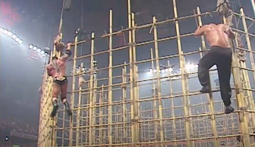 Two men climbing down a bamboo cage.