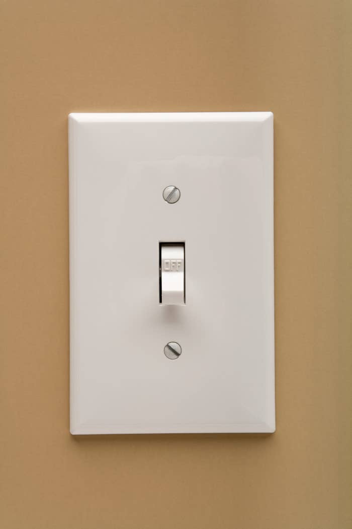 A white light switch on a sand-colored wall.