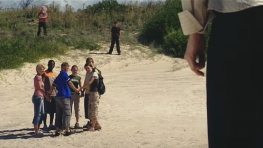 Characters from Jeopardy standing in a circle while holding hands on a beach