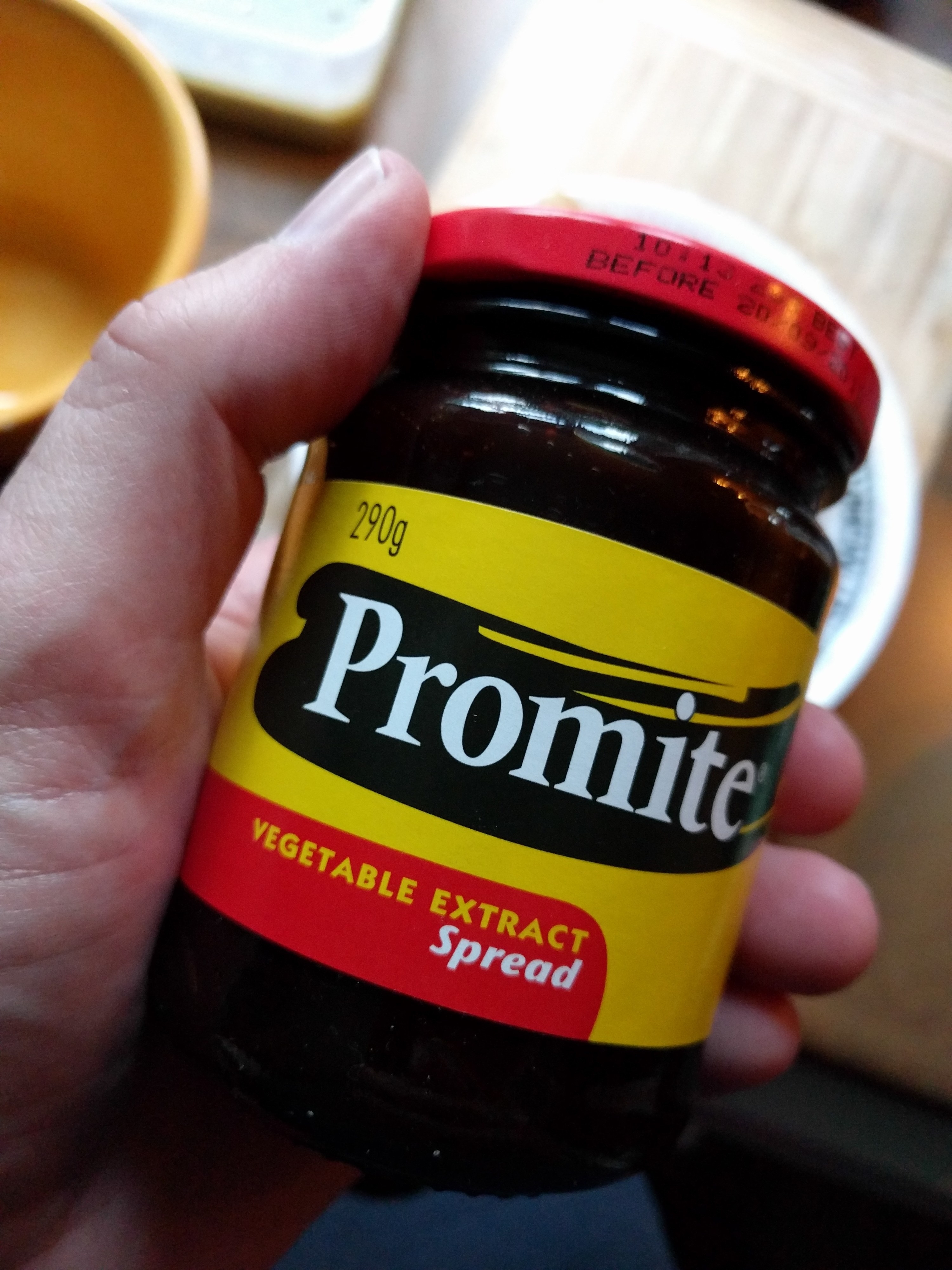 A hand holding a jar of Promite