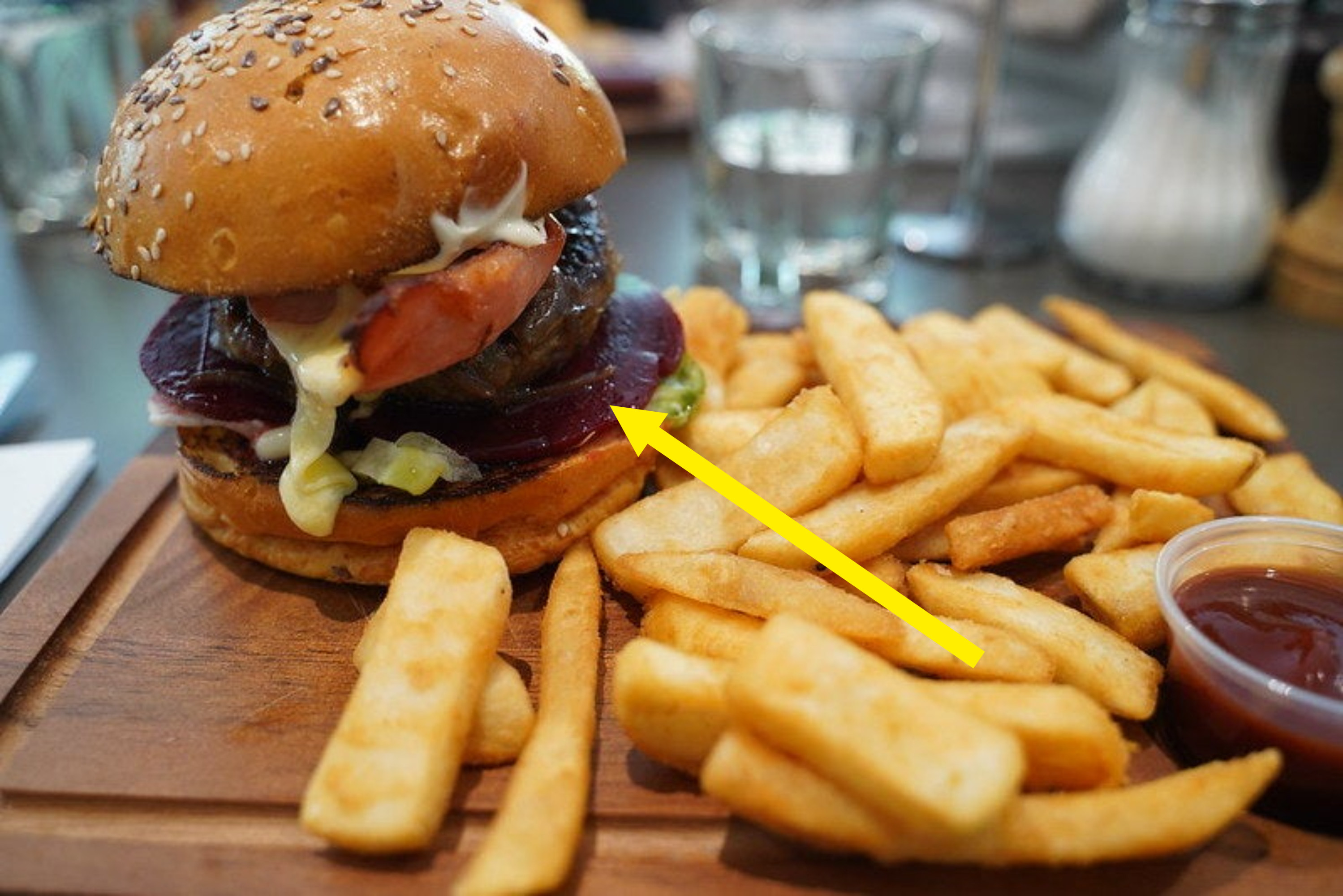 A serving board with an Aussie burger (with beetroot) and chips