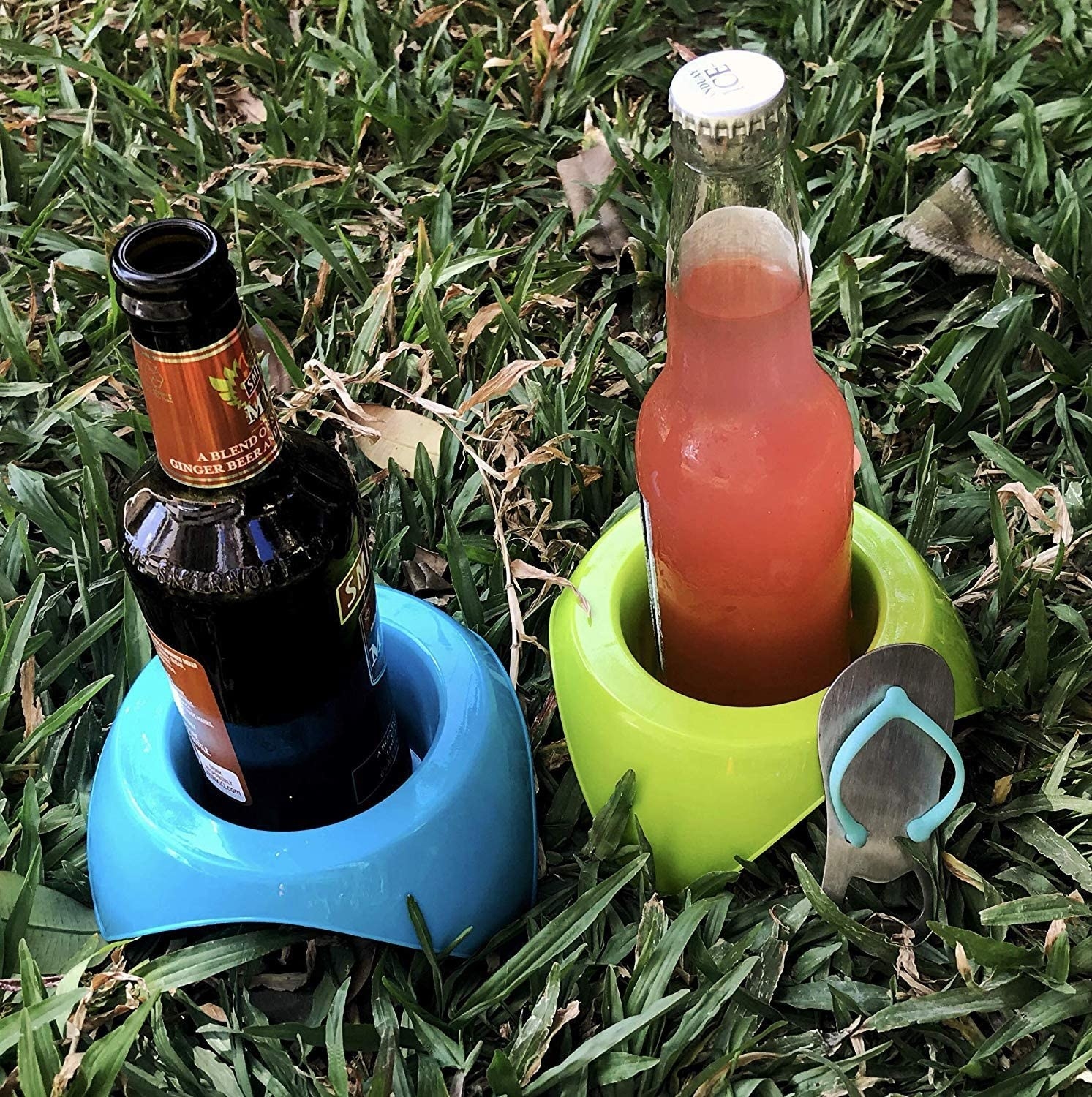 A pair of bottles in two cup holders in some grass