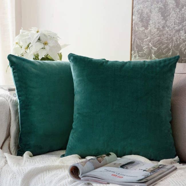 two green velvet throw pillows on a couch