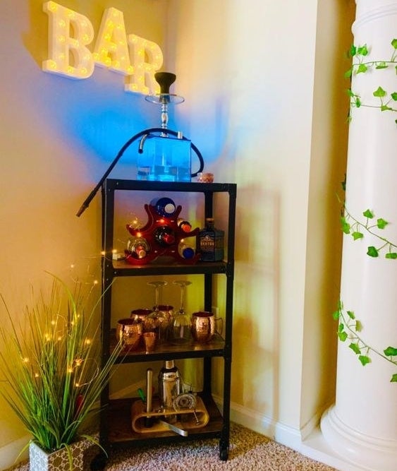 Reviewer using the bar cart to show Moscow mule glasses, fancy bottles, and more