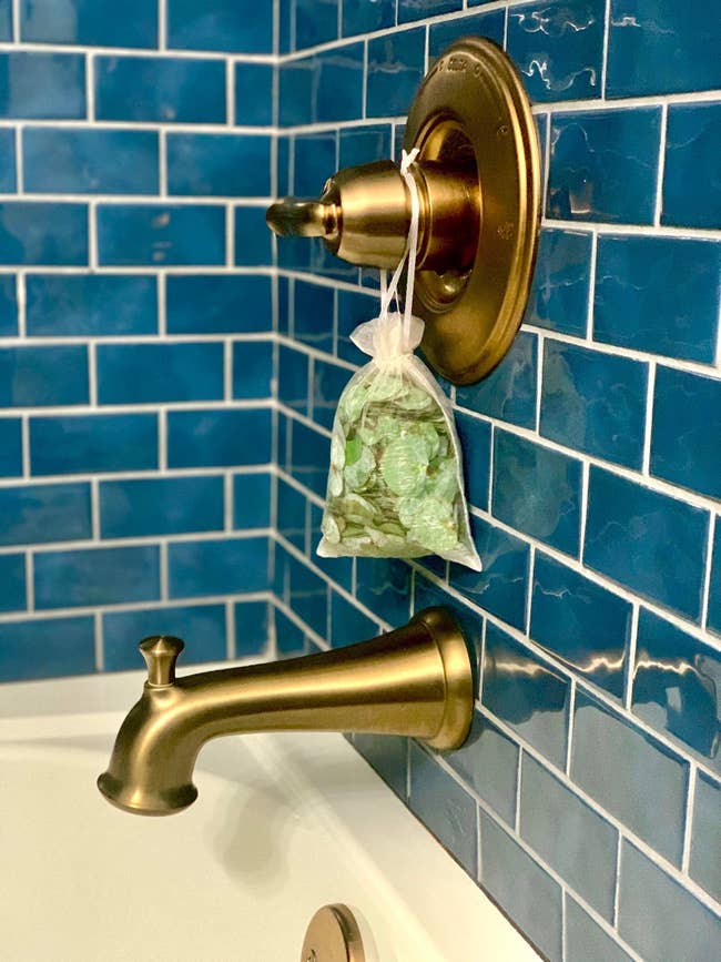 a eucalyptus shower pouch hanging from a bathtub's handle valve
