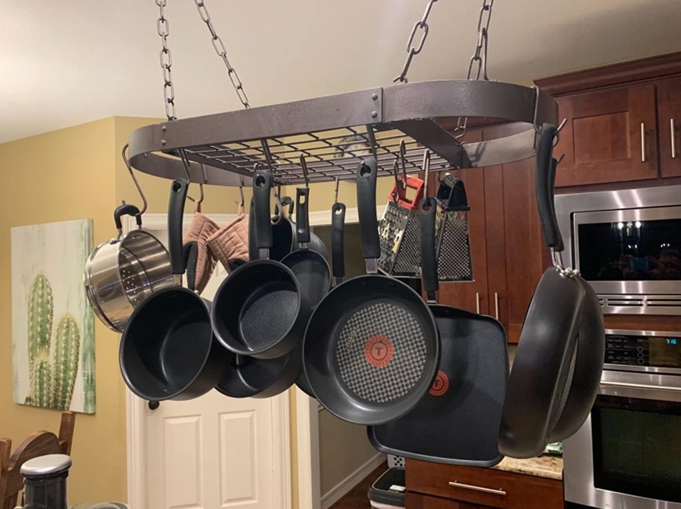 The reviewer&#x27;s photo of the 17 piece nonstick cookware set hanging in a kitchen