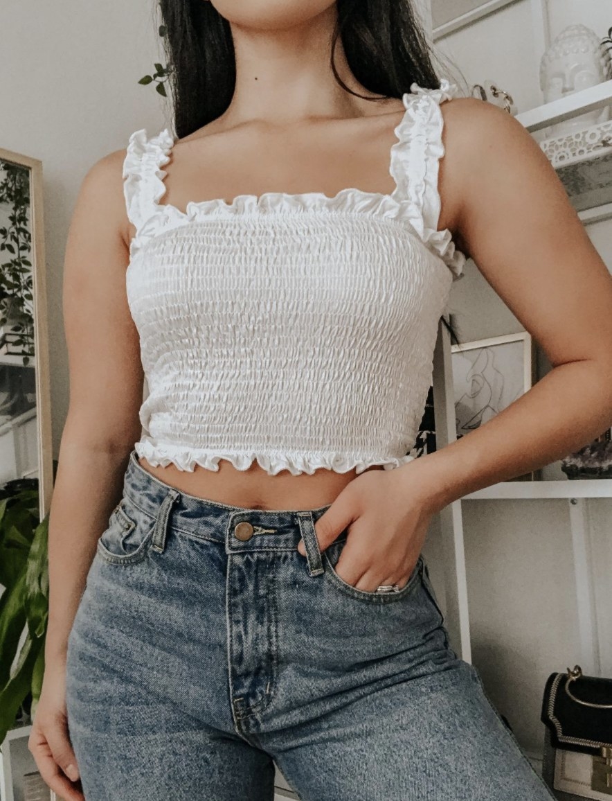 Person is wearing a white smocked crop top and jeans
