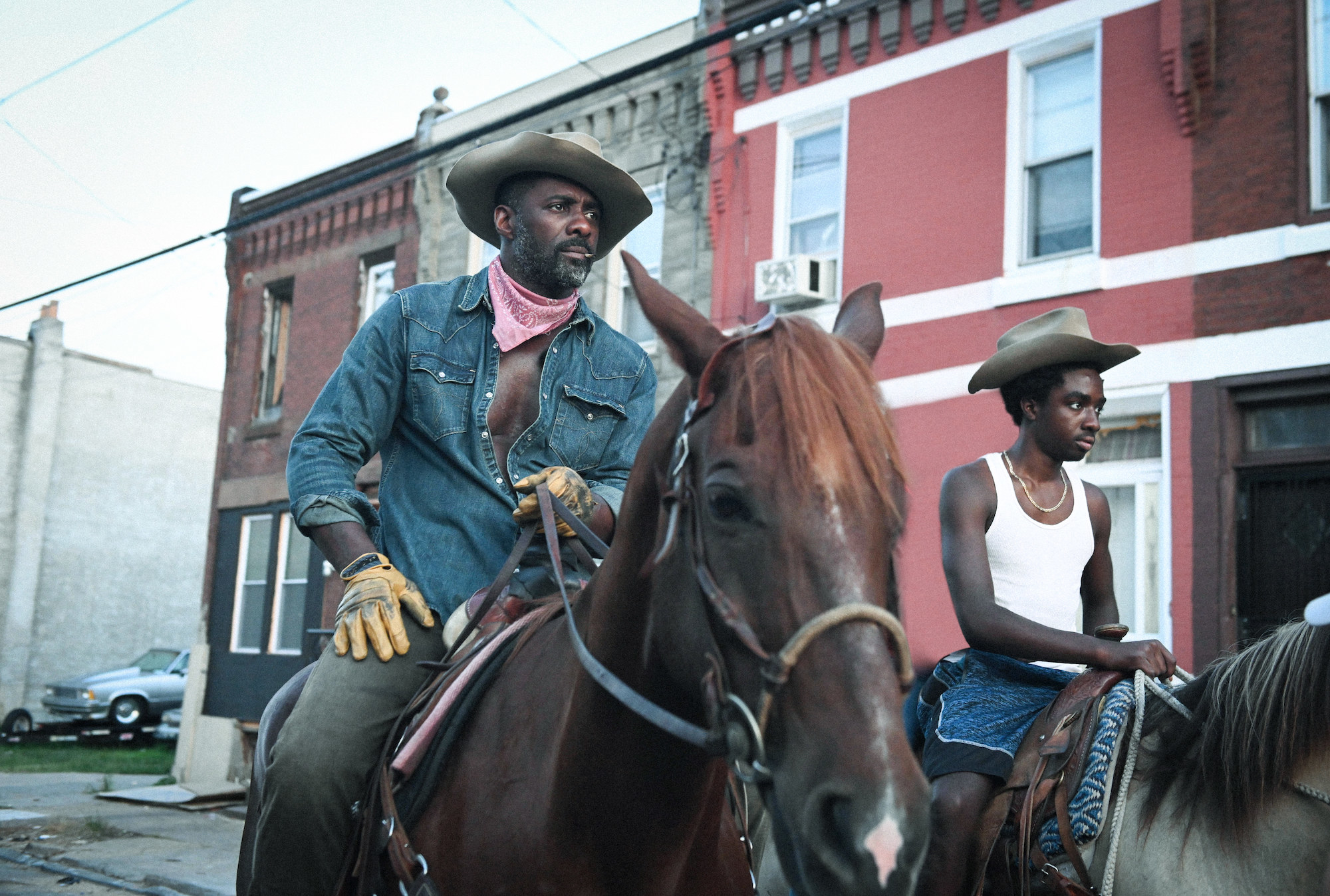 Idris Elba and Caleb McLaughlin riding horses through town in Concrete Cowboy