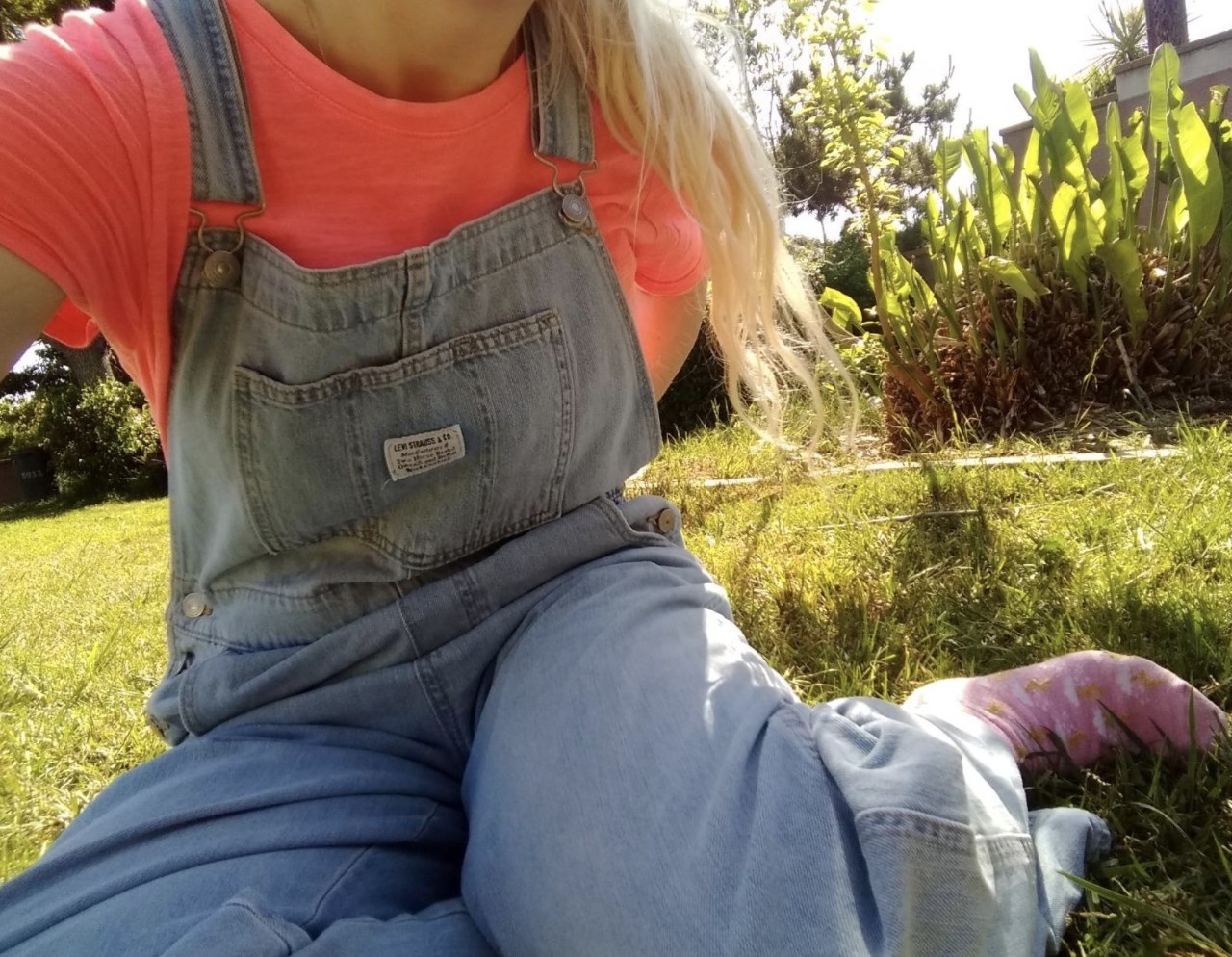 Person is wearing light denim overalls and a pink top