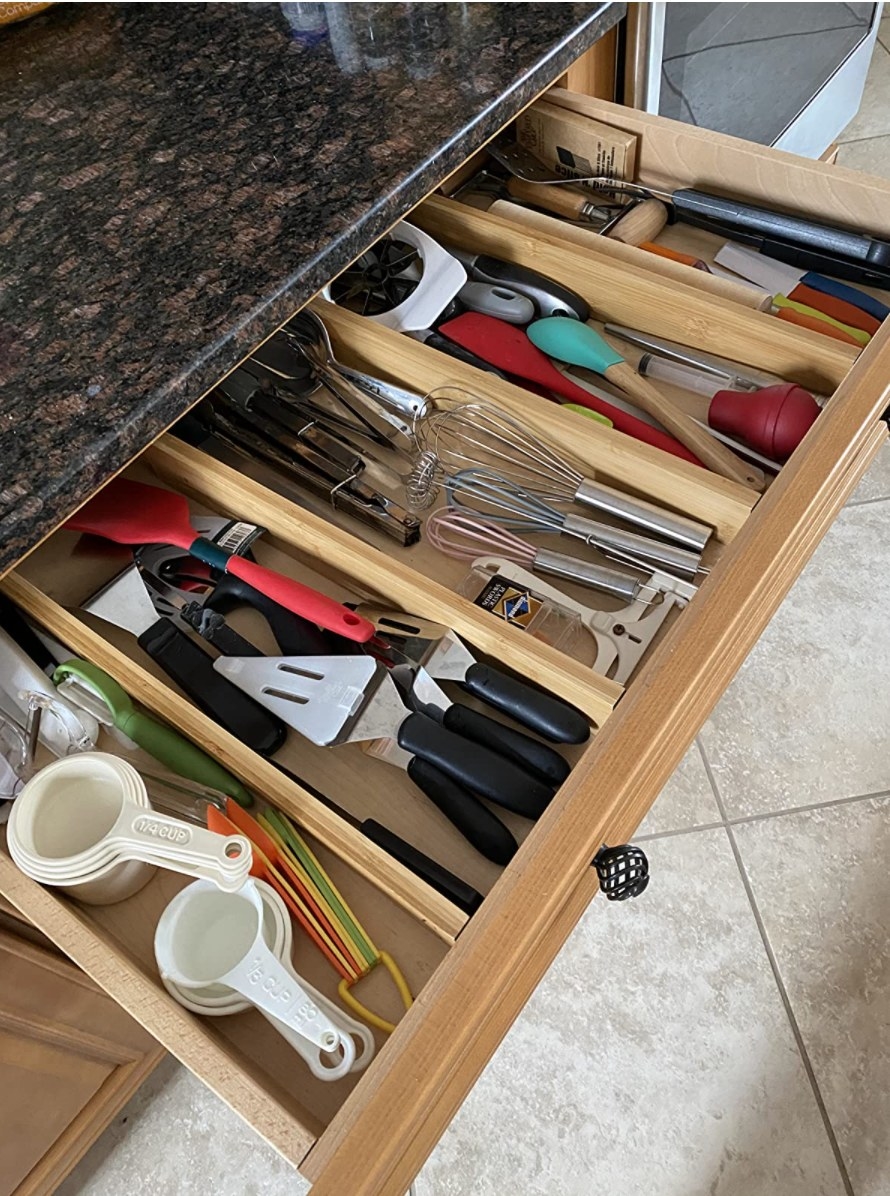 The bamboo drawer organizer with utensils in it