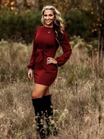 Reviewer photo of a person wearing a wine red knit dress and black boots