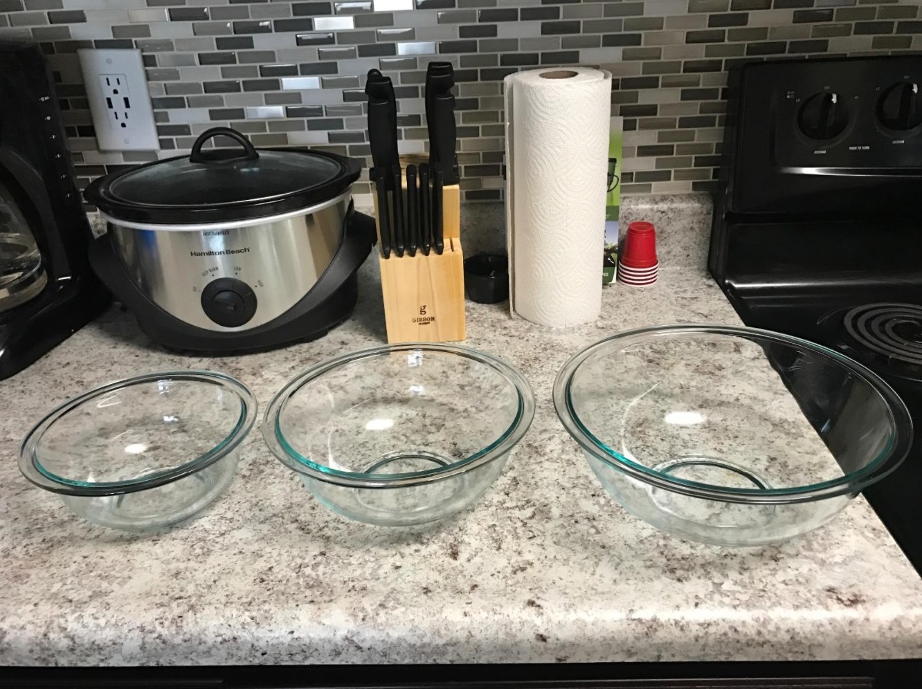 The reviewer&#x27;s photo of the three glass mixing bowls on their granite counter