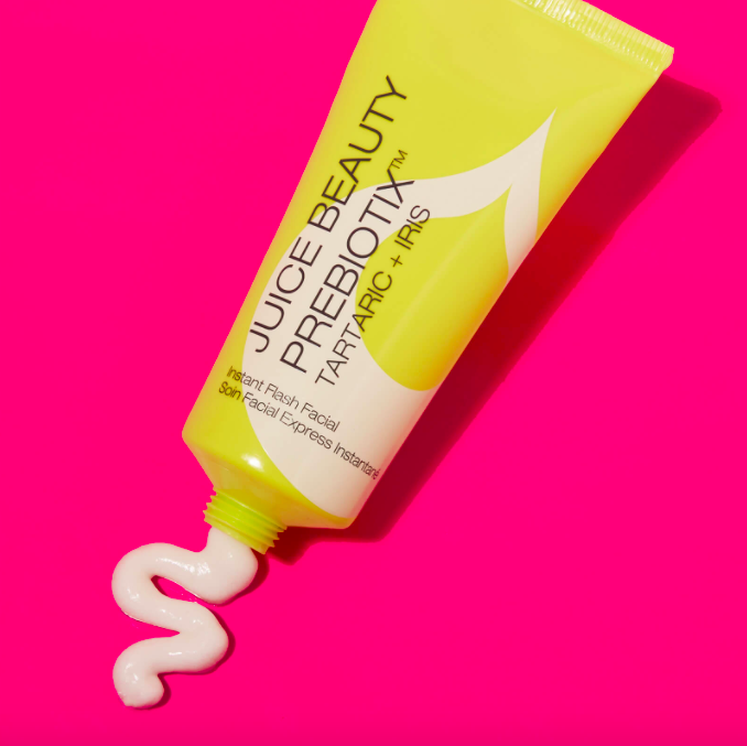 A flatlay of a tube of the product squeezing some out onto a colourful background