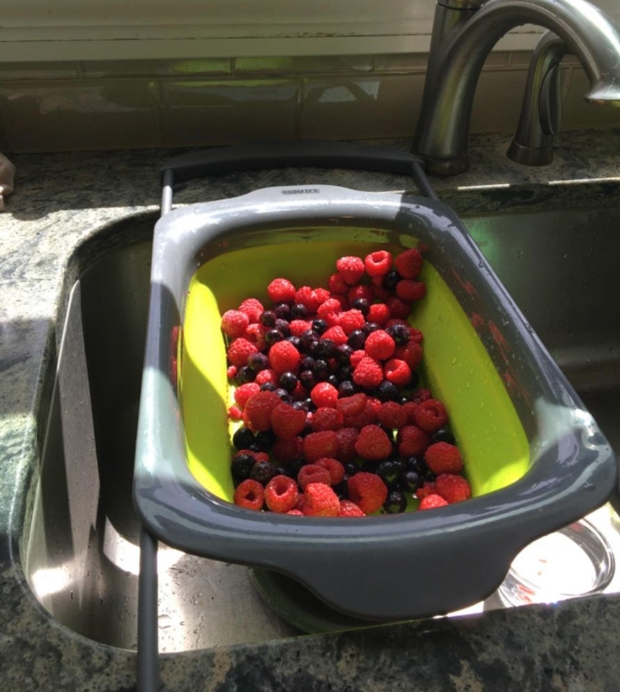 The reviewer&#x27;s photo of the green collapsable strainer in their sink