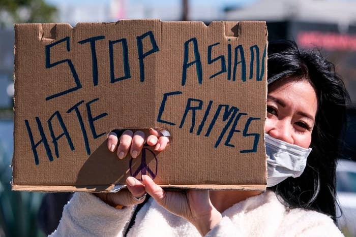 Woman holding up a sign that says &quot;Stop Asian hate crimes&quot;