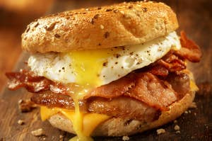 a breakfast sandwich oozing egg over bacon