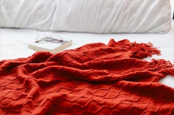 an orange throw blanket on a bed
