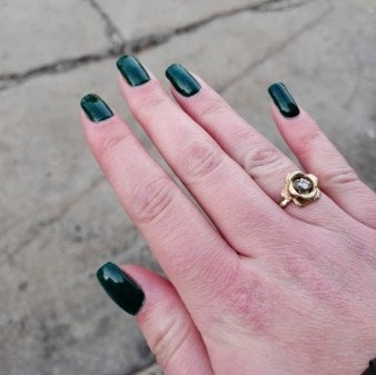 person with dark green at home manicure
