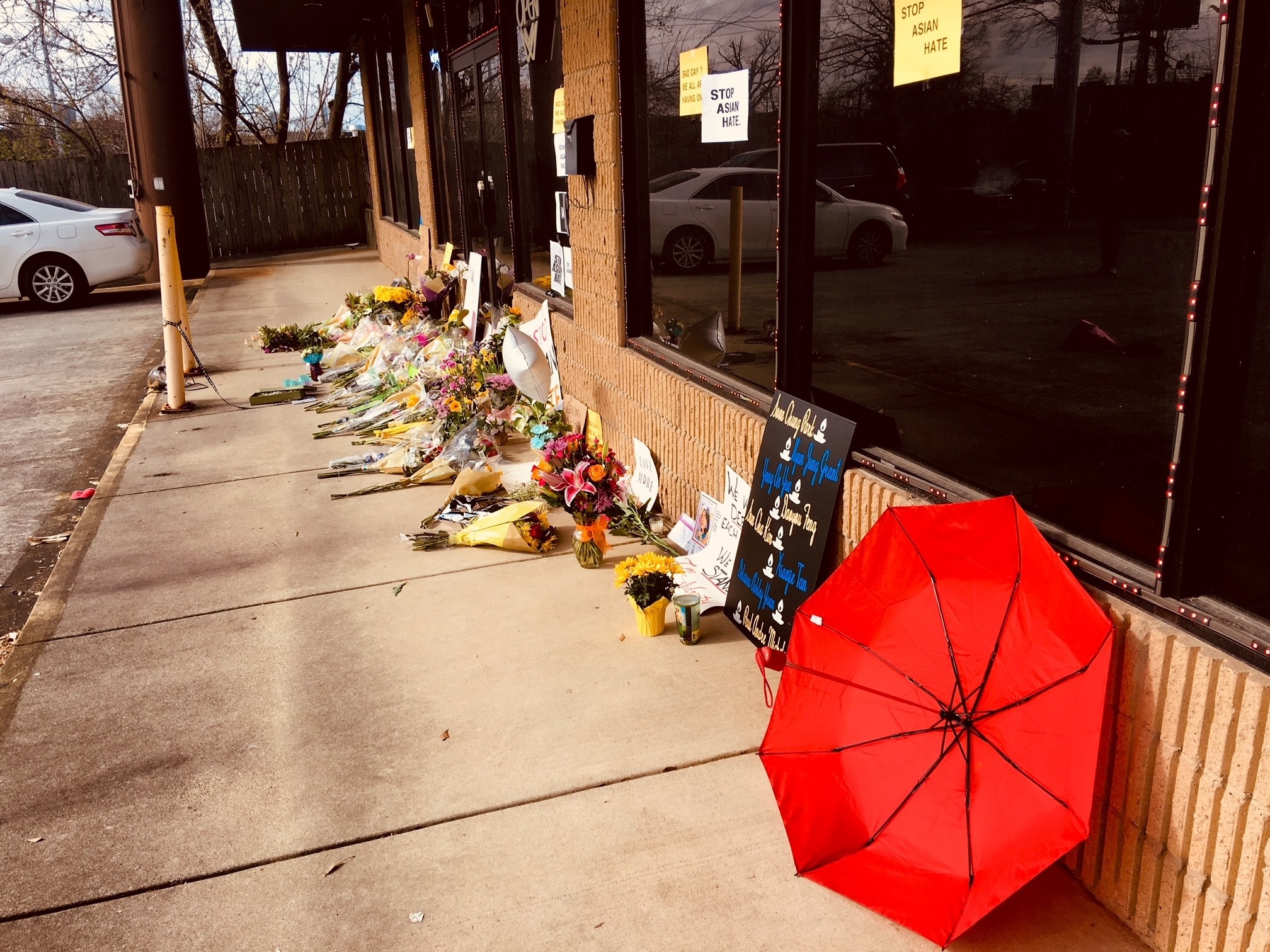 A red umbrella and memorials outside a storefront