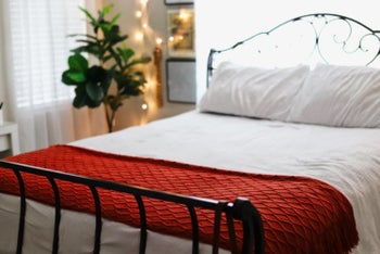 reviewer's rust orange blanket folded on the foot of a bed