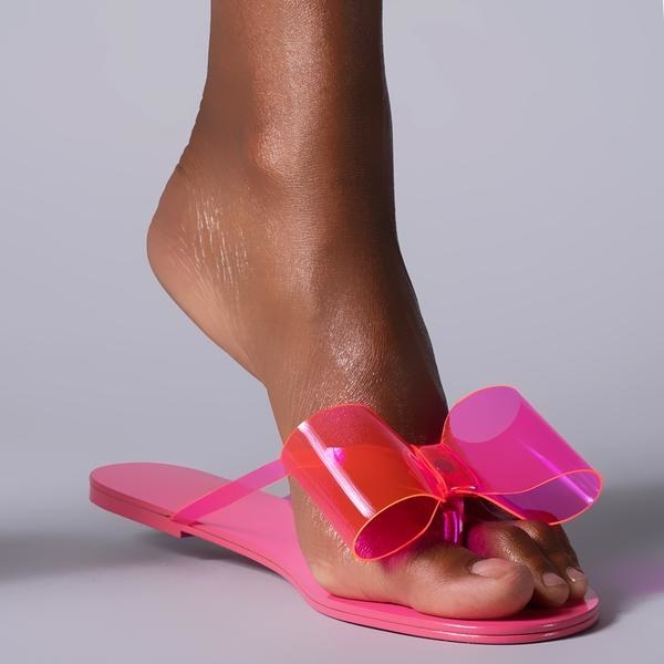 model wears pink jelly material flip-flops with bow detailing