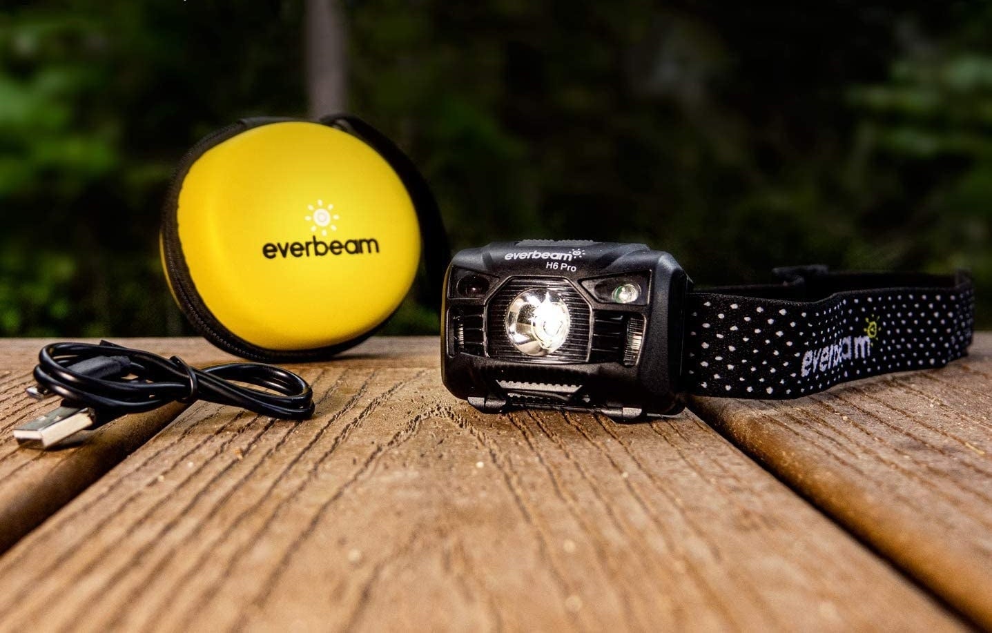 The rechargeable headlamp next to a USB cord and a small, round, protective case