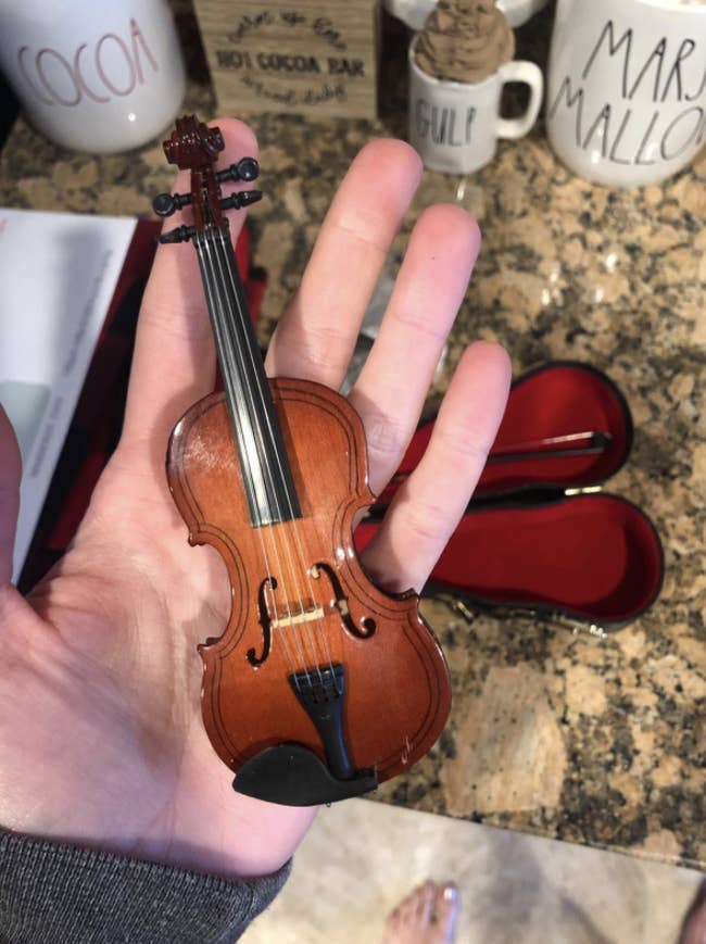 a reviewer holding the miniature violin
