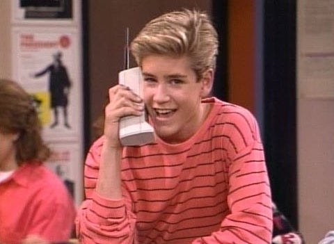 Zack Morris looking at the camera as he talks on his &#x27;90s cellphone 
