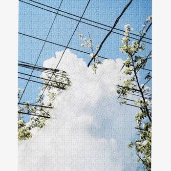 the completed puzzle with the image of a blue sky and fluffy white clouds