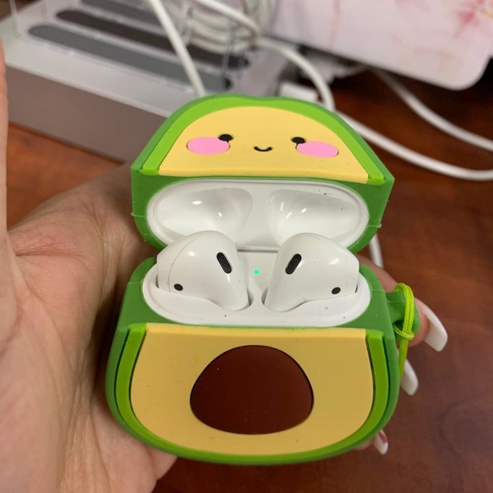 Reviewer holding opened avocado-shaped AirPods case