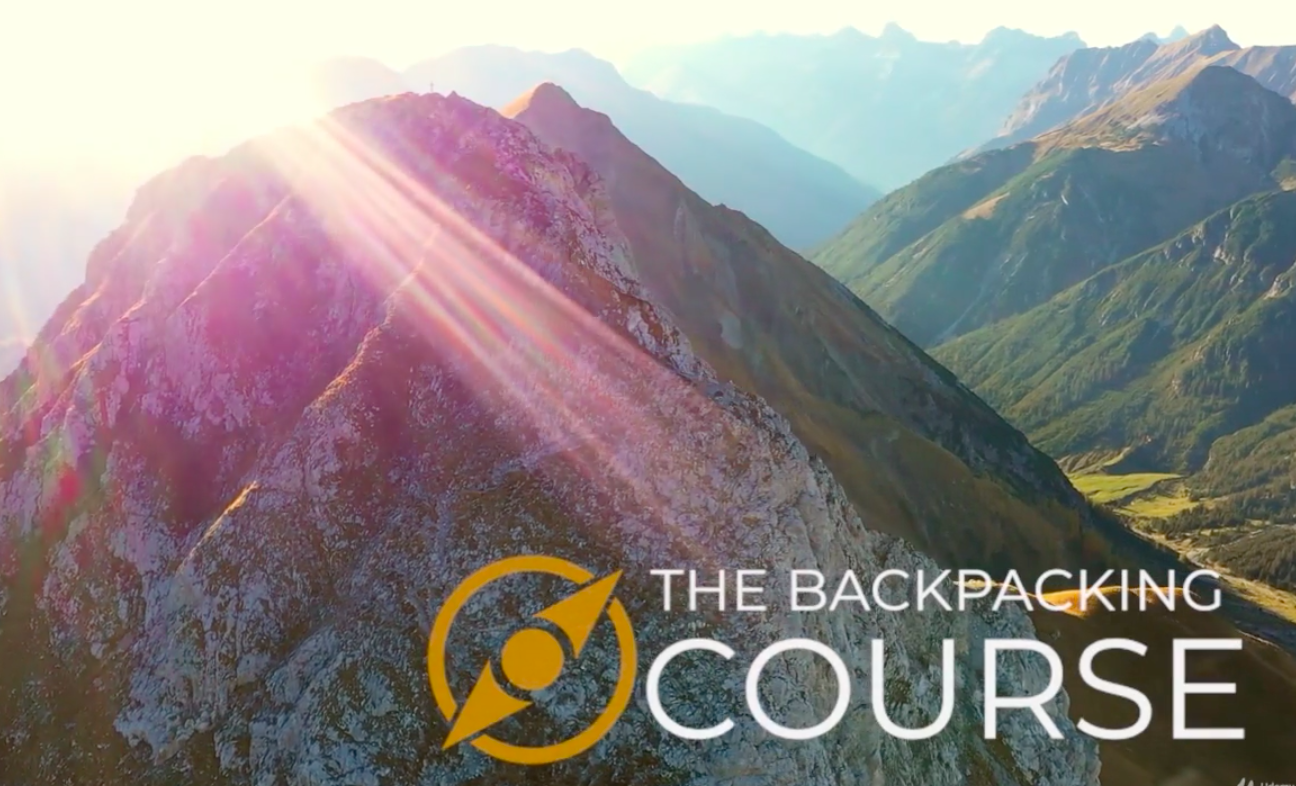 A mountainous range in the sunshine with the words the backpacking course written across it