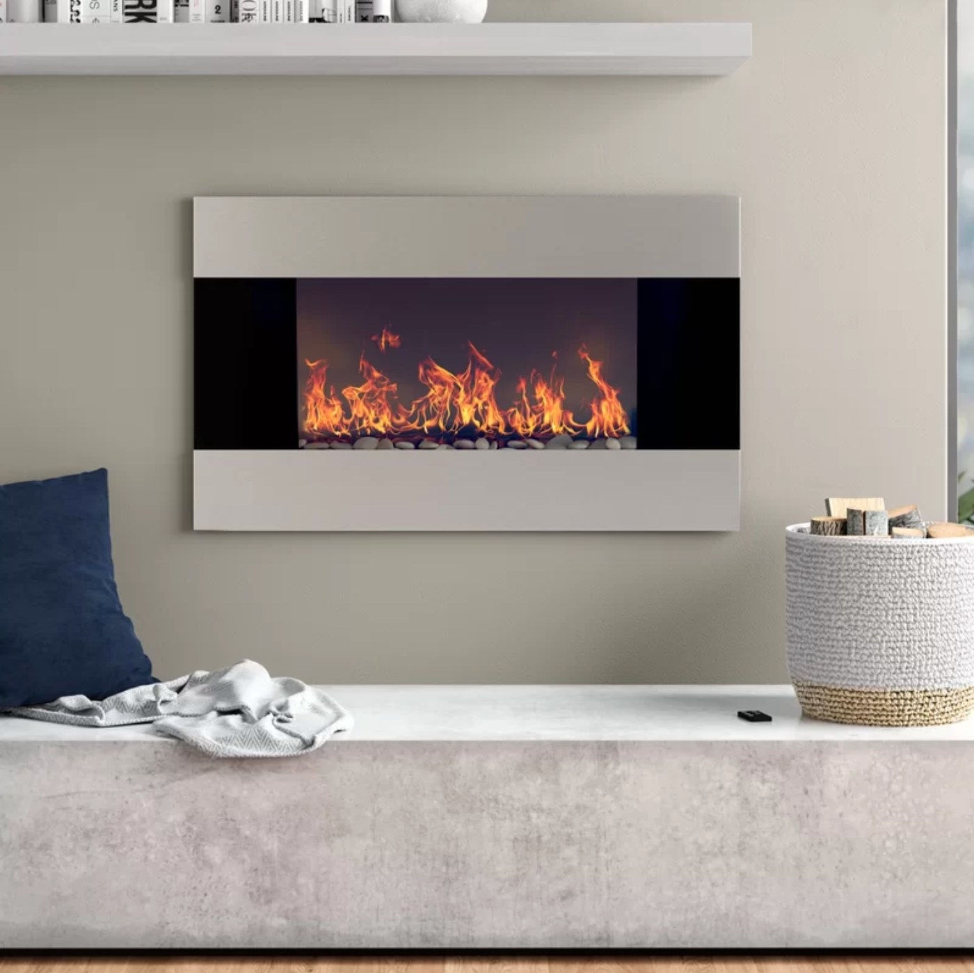 The electric mounted wall fireplace above a gray fabric bench