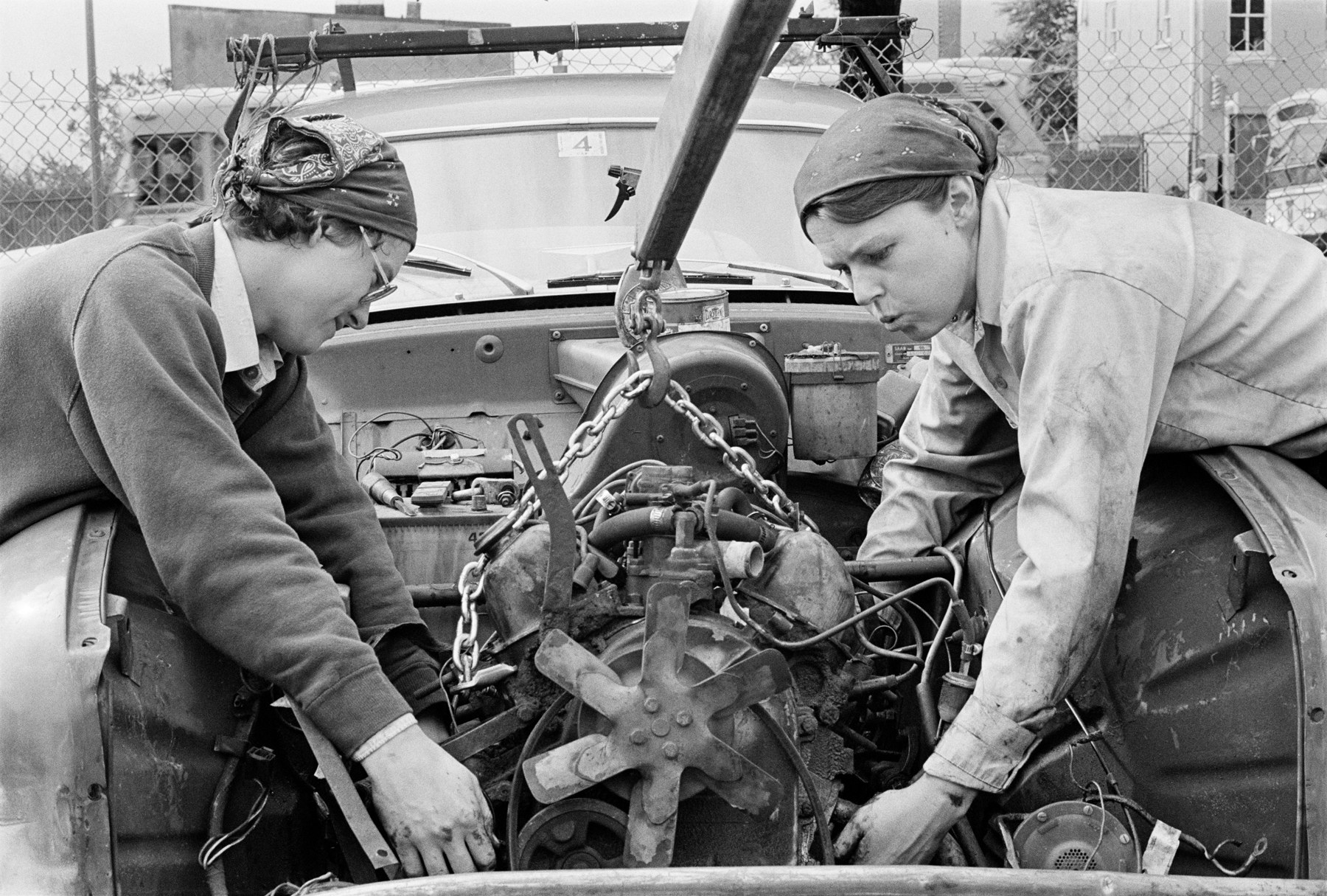 Two women work on a car engine