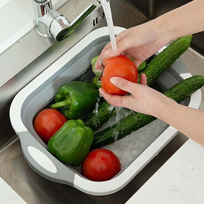 Person washing vegetables on the collapsible board.