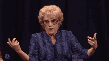 Kate McKinnon dressed as an older woman shrugs and rolls her eyes aggressively 