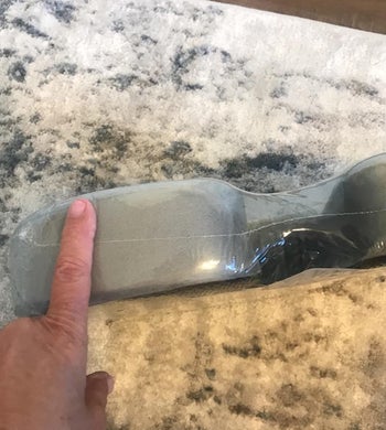 reviewer showing the thickness of the cushion, it's as thick as their finger is long 