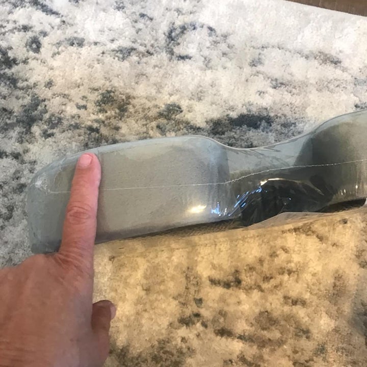 reviewer showing the thickness of the cushion, it's as thick as their finger is long 