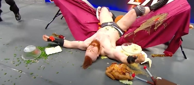 Wrestler Sheamus lying on a broken table with Thanksgiving food scattered on the ground.