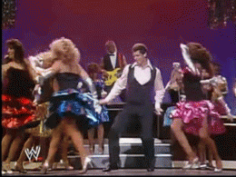 Vince McMahon trying to dance while Hulk Hogan pretends to play guitar in the background.
