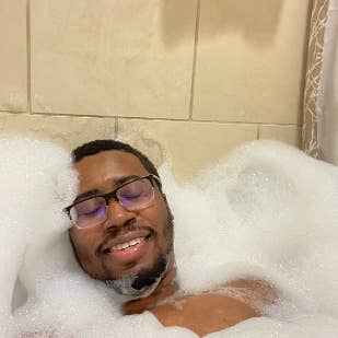 Reviewer closing their eyes and smiling while in a bath filled with tons of bubbles 