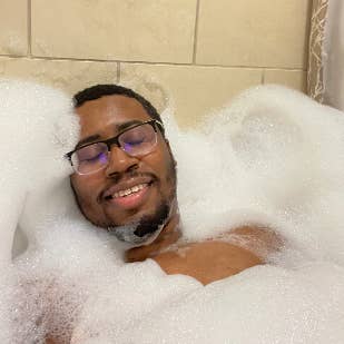 Reviewer closing their eyes and smiling while in a bath filled with tons of bubbles 