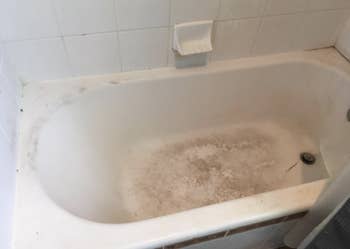 A customer review before photo of their white tub with dark brown stains in the corners and on the floor