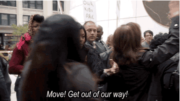 Women moving through a crowd saying, &quot;move! get out of our way&quot;