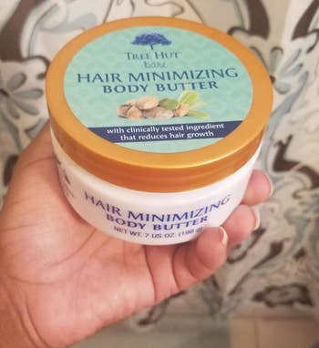 Reviewer holding tub of Tree Hut Hair Minimizing Body Butter