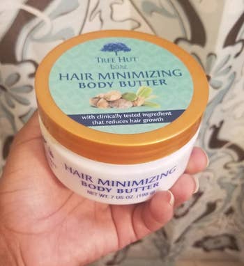 Reviewer holding tub of Tree Hut Hair Minimizing Body Butter