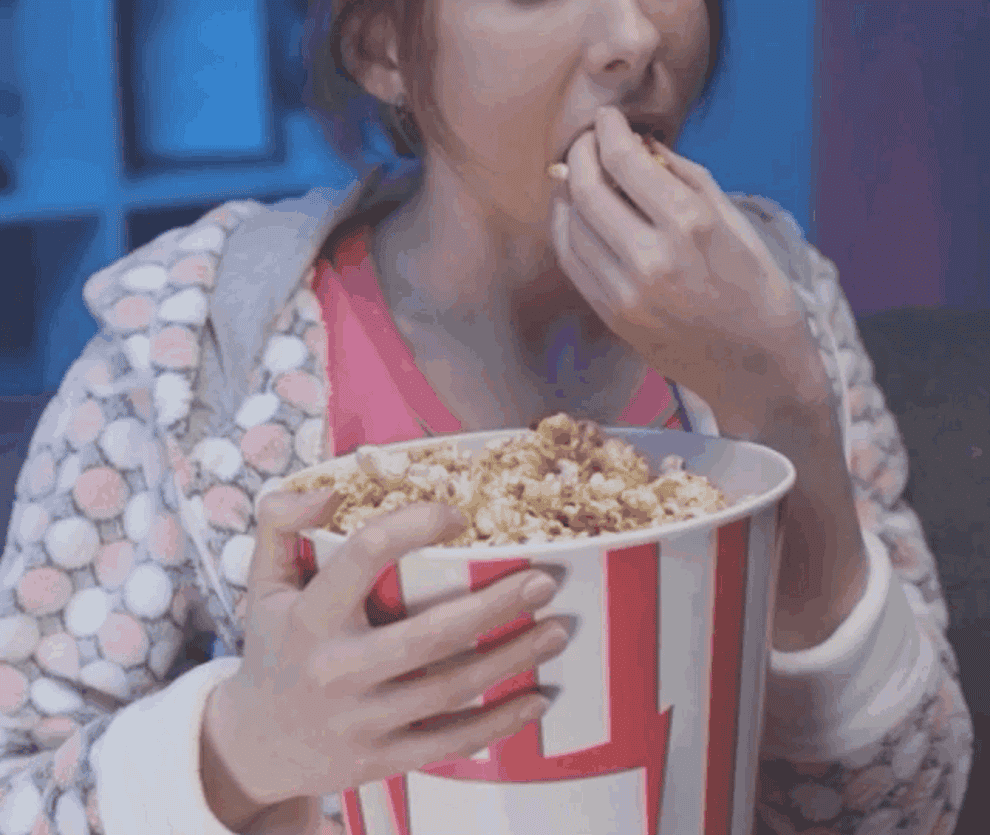 Person chomping on a big bucket of popcorn 