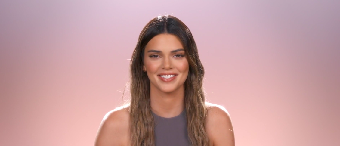 A happy Kylie in front of a pink and purple background