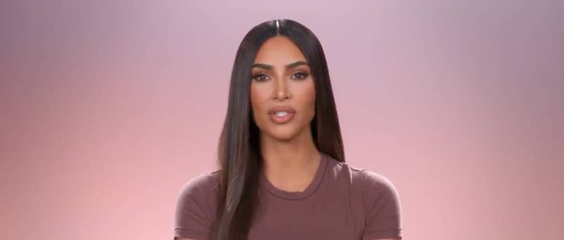 Kim speaking in front of a pink and purple background