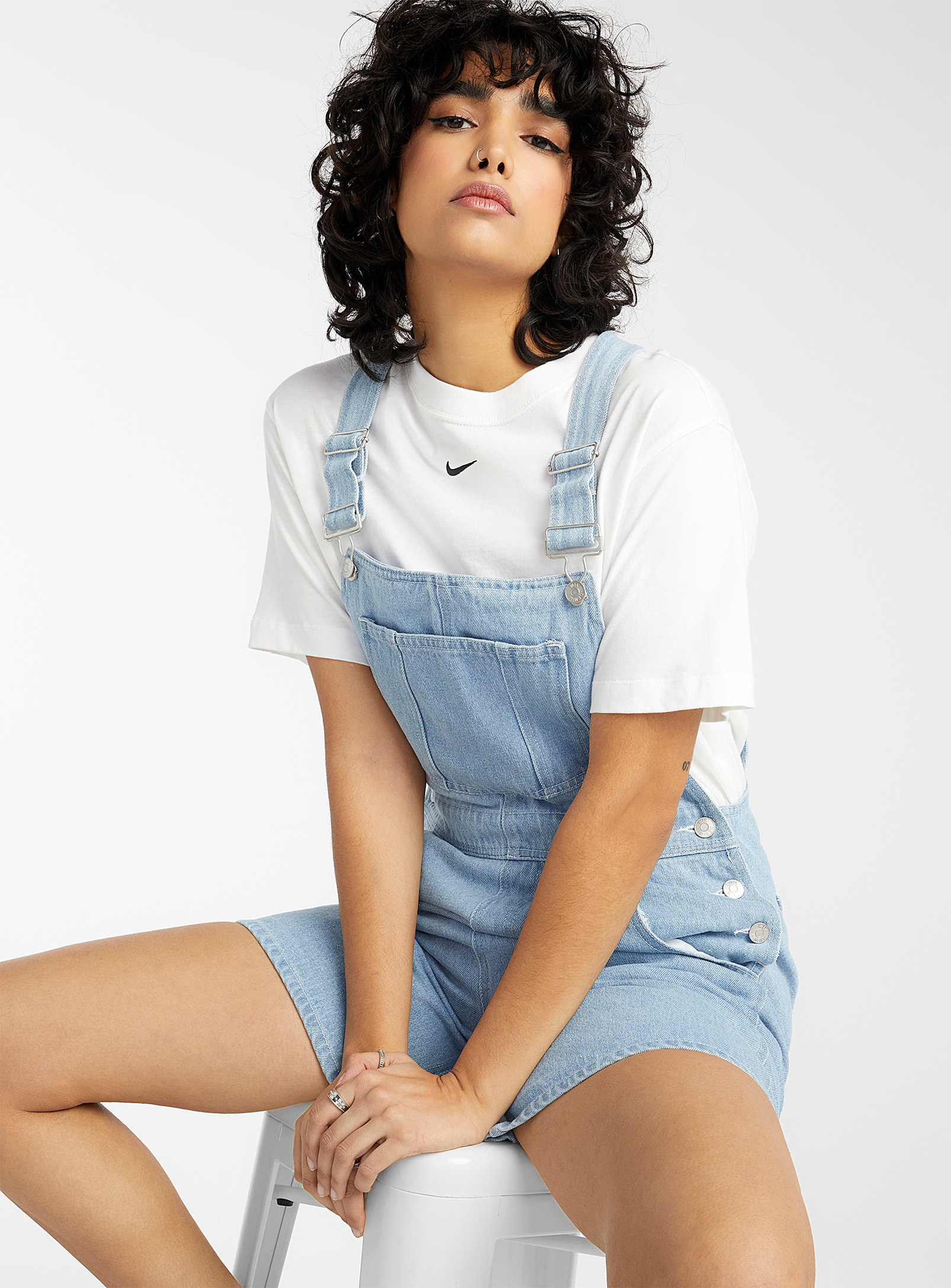 A person wearing a pair of overalls with a T-shirt